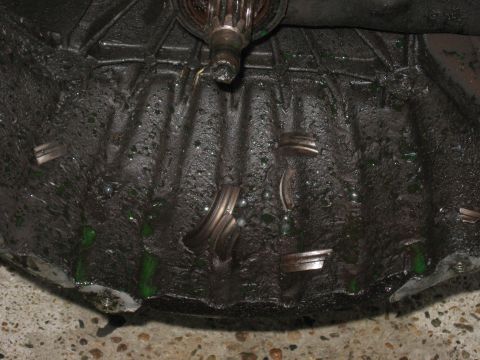 1981 Ford Bronco - Close-up view of a transmission bell housing showing green fluid and metal fragments, suggesting internal damage.