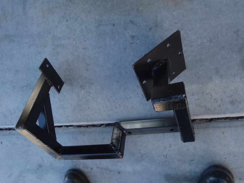 two black metal brackets welded together, one with a triangular brace