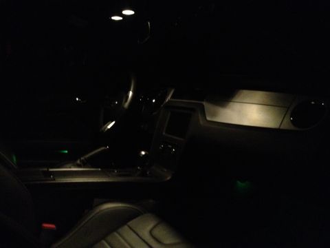 2013 Ford Mustang - The interior of a car is dimly lit at night, revealing the dashboard and seats.