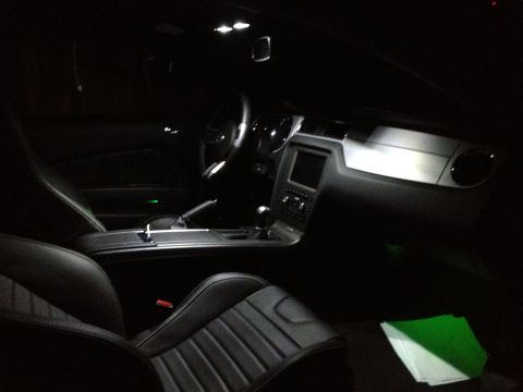 2013 Ford Mustang - The interior of a 2013 Ford Mustang features black leather seats and a modern dashboard illuminated by interior lights.