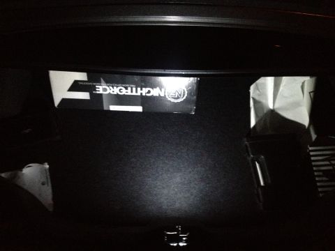 2013 Ford Mustang - The trunk of a vehicle contains a box labeled NIGHTFORCE and a white bag.