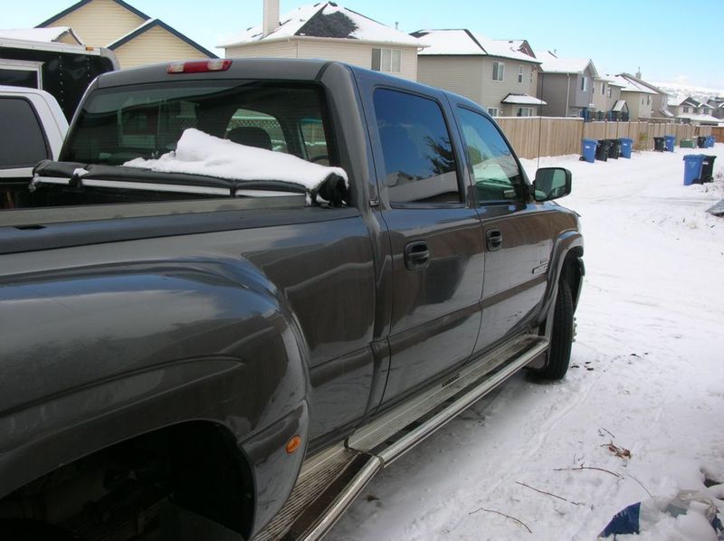 Dark gray dually pickup truck, 3/4 front view, snow on bed cover