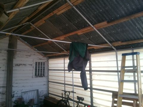 1966 Ford Bronco - Interior view of a shed with a bicycle, ladder, and clothes hanging from a bar.