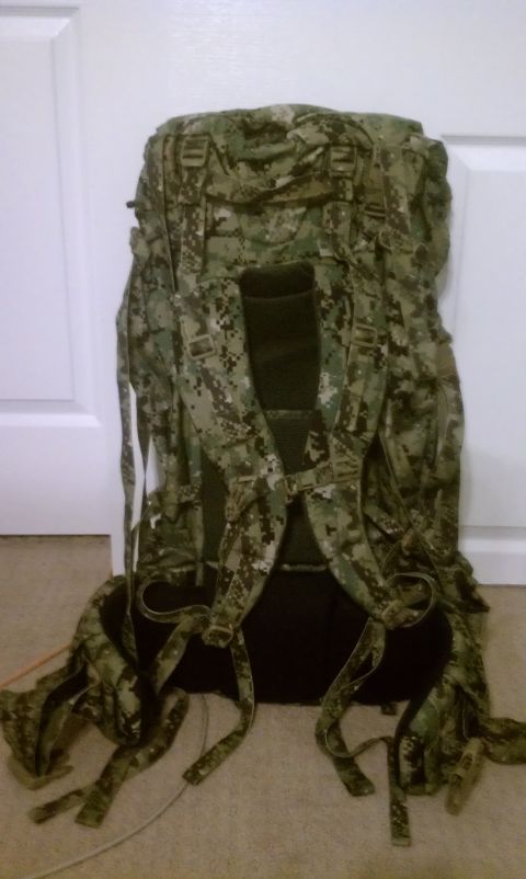 1989 Ford Bronco - A camouflage backpack stands against a white door and carpeted floor.