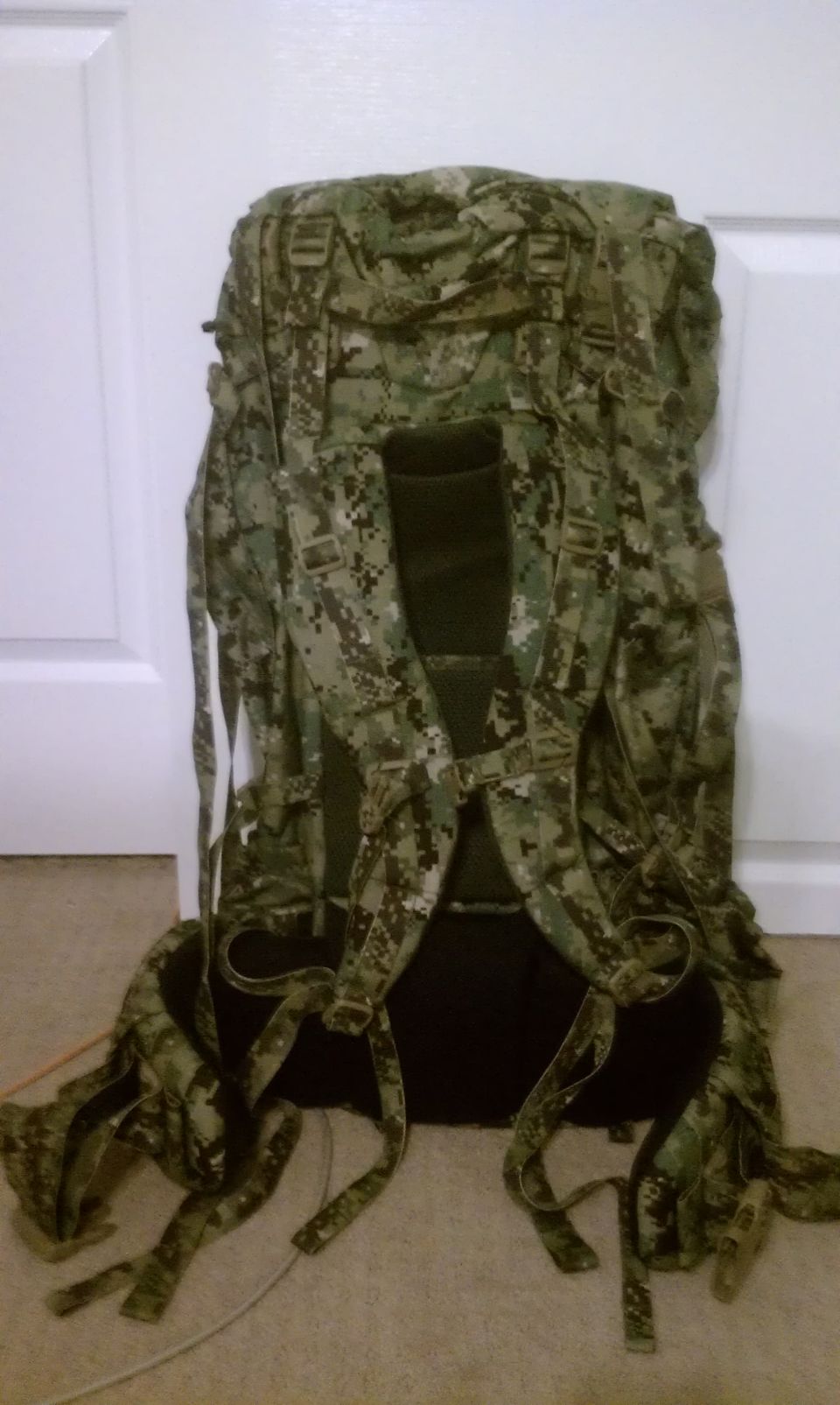 Back view of a large camouflage backpack with many straps and buckles