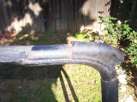 1990 Ford Bronco - A section of a black metal roll bar, showing signs of wear and tear, is pictured outdoors.