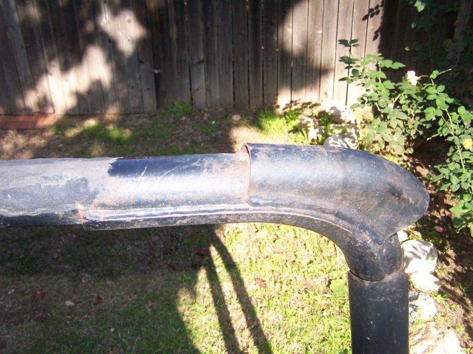 black metal roll bar section with rust and chipped paint, outdoors