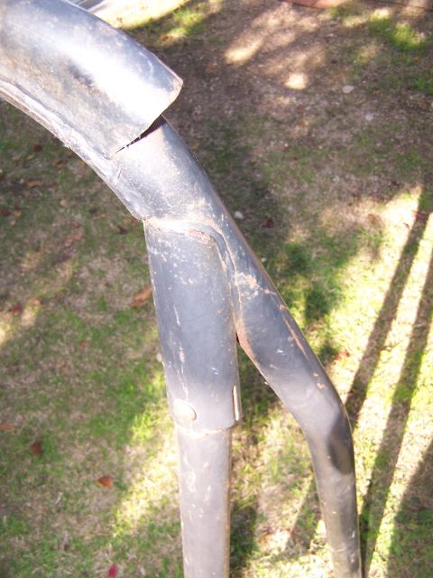 1990 Ford Bronco - A close-up of a damaged black metal roll bar, showing signs of wear and tear.