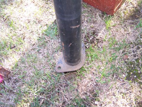 1990 Ford Bronco - Close-up of a metal pole with a flange, resting on grass and dirt.