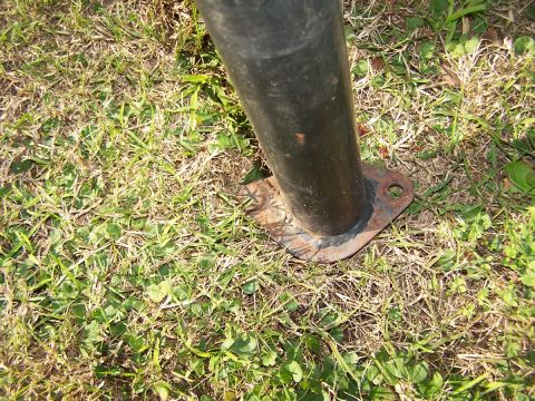 1990 Ford Bronco - A close-up view of a roll bar's mounting point secured to the ground.