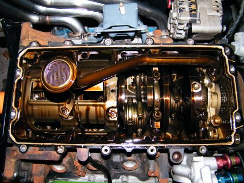 2004 Ford Crown Victoria - Close-up view of an engine's internal components with the oil pan removed, revealing the crankshaft and connecting rods.