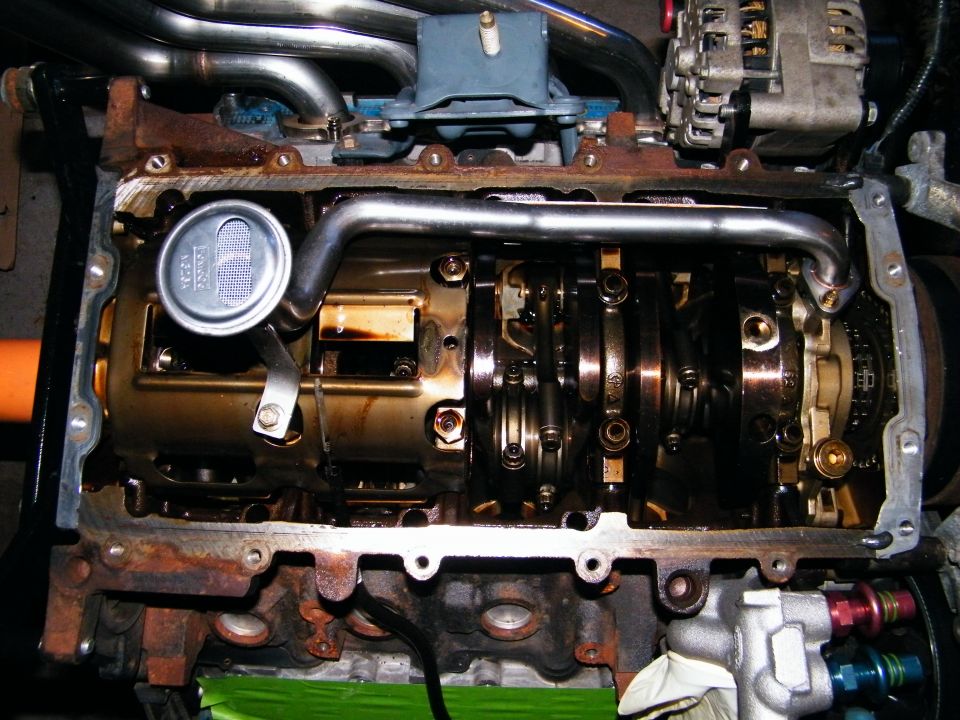 engine block with crankshaft, connecting rods, and oil pump visible. Headers and alternator also present