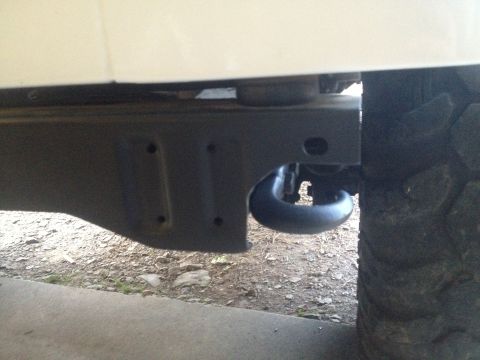 2000 Jeep TJ - Close-up view of a tow hook mounted on the frame of a vehicle, with a tire visible to the right.