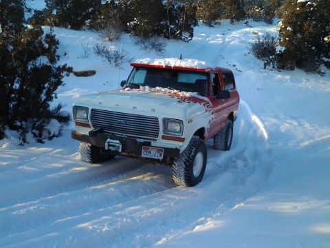 1979 Ford Bronco - This 1979 Ford Bronco navigates a snowy terrain, its distinctive red and white paint job visible against the winter landscape.
