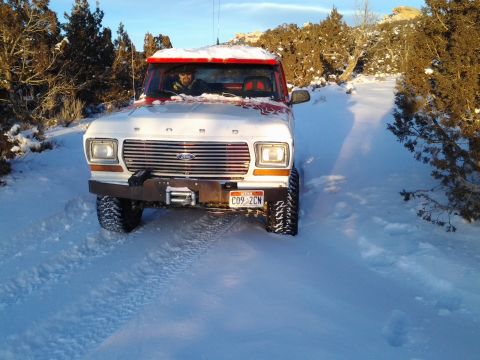 1979 Ford Bronco - A 1979 Ford Bronco navigates a snow-covered path, its front grille and headlights clearly visible.