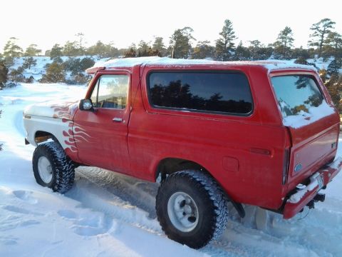 1979 Ford Bronco - A red and white 1978 Ford Bronco with flame decals drives through the snow.