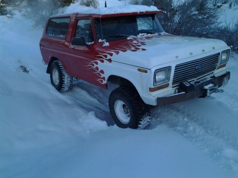 1979 Ford Bronco - This red and white Ford Bronco is navigating a snowy, off-road path.