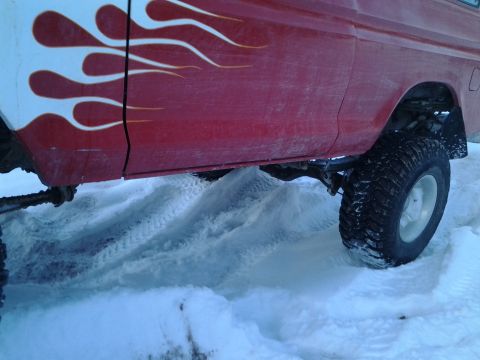 1979 Ford Bronco - A red truck with flame decals navigates through a snowy terrain.