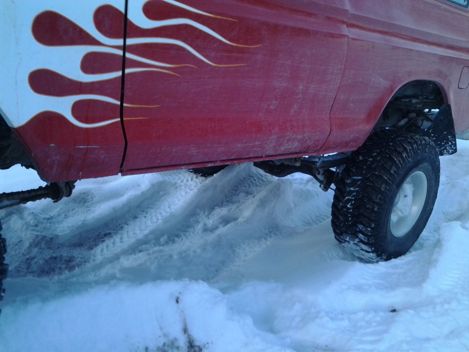Red truck side view with white and orange flame decals, driving in snow
