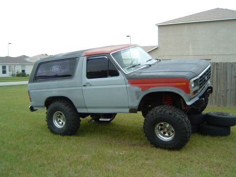 1983 Ford Bronco - This lifted Ford Bronco appears to be from the early 1980s, a primer gray body with red accents on the hood and roof.