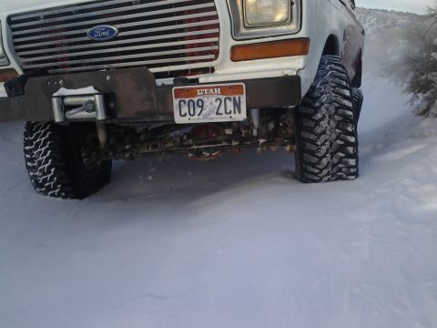 1979 Ford Bronco - This 1978 Ford Bronco's front end is visible in a snowy landscape, equipped with a winch and aggressive tires.