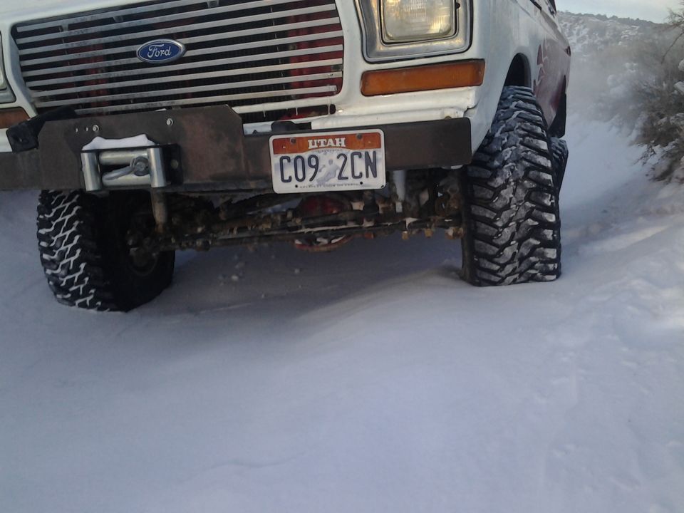 White 1978 Ford Bronco front end with winch, Utah license plate, and large off-road tires in snow