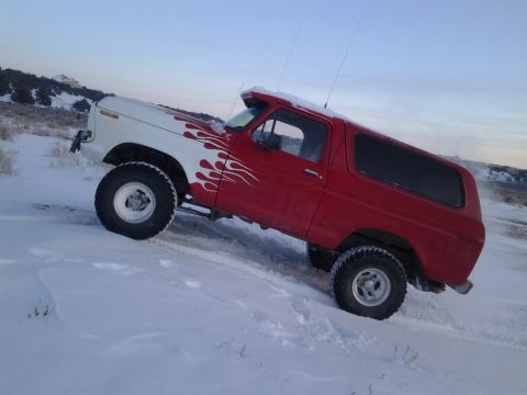 1979 Ford Bronco - This SUV, likely a 1978 Ford Bronco, navigates a snowy terrain with custom flame graphics on its hood.