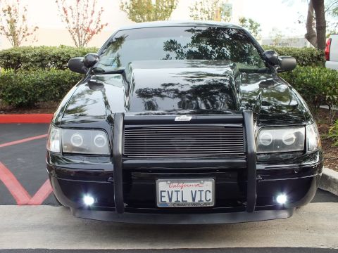2003 Ford Crown Victoria - Front of a blacked-out Crown Victoria sedan with halo headlights, push bumper and an EVIL VIC vanity plate.