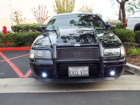 2003 Ford Crown Victoria - Front three-quarter of a black Crown Victoria with push bar, billet grille and illuminated white fog lamps.