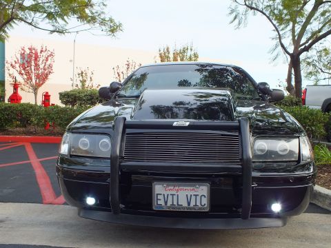 2003 Ford Crown Victoria - Front view of a blacked-out Crown Victoria showing halo headlights, push bar and lit fog lamps.