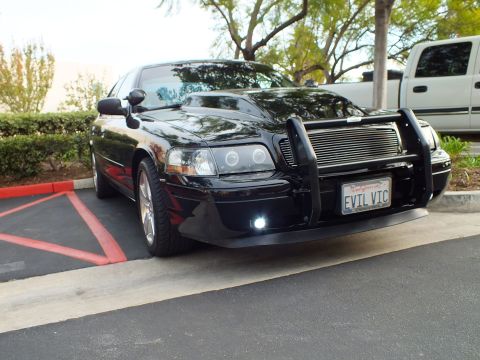 2003 Ford Crown Victoria - Angled front view of a lowered blacked-out Crown Victoria with push bar and lit white fog lamps.