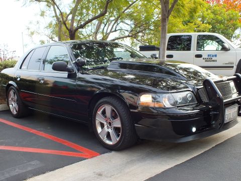 2003 Ford Crown Victoria - Full side three-quarter of a blacked-out Crown Victoria with chrome wheels and a front push bar.