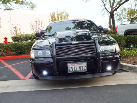 2003 Ford Crown Victoria - Front end of a blacked-out Crown Victoria, push bar and EVIL VIC plate, parked at a strip mall lot.