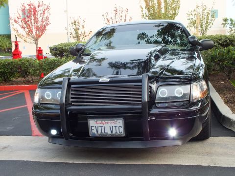 2003 Ford Crown Victoria - Slightly angled front of a black Crown Victoria, halo headlights and grille guard, EVIL VIC California tag.