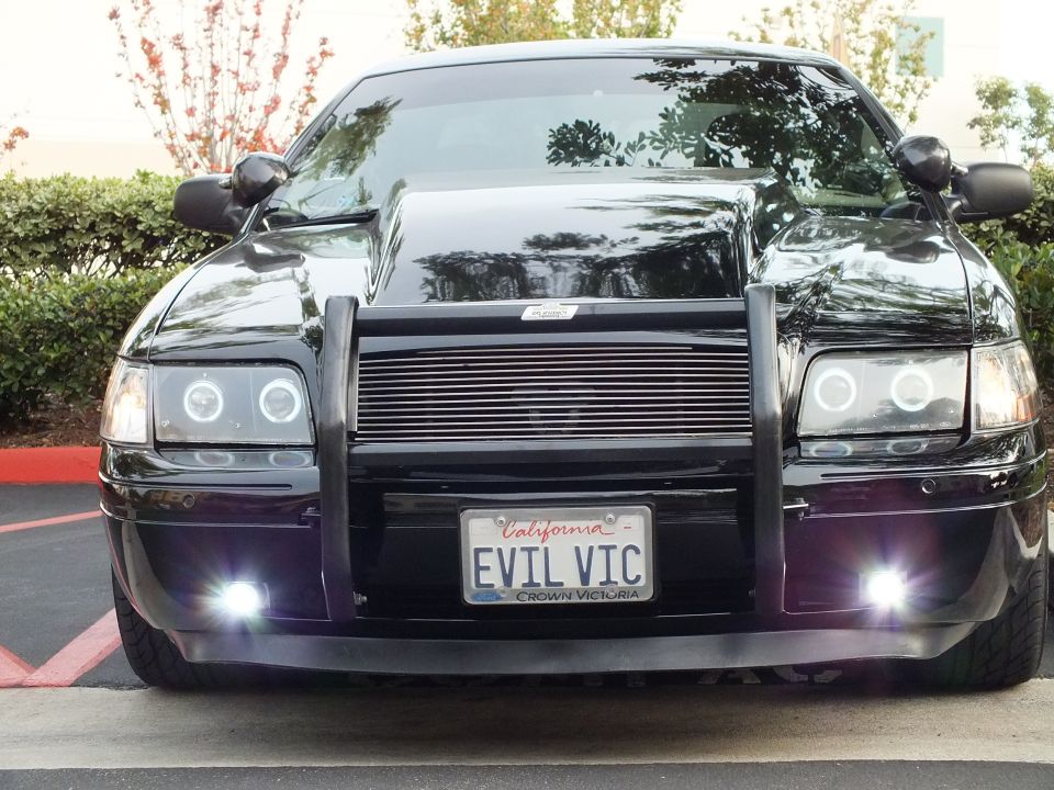 Black Crown Victoria front with billet grille, halo headlights and EVIL VIC plate at parking lot