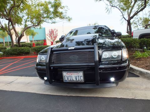 2003 Ford Crown Victoria - Head-on shot of a low black Crown Victoria, halo projector lamps and single white foglight illuminated.