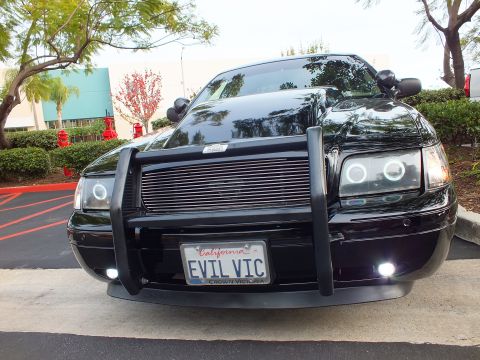 2003 Ford Crown Victoria - Crown Victoria nose with grille guard, smoked projector halos and white foglights, parked on asphalt.