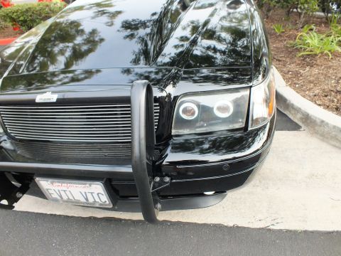 2003 Ford Crown Victoria - Tight angle on a Crown Victoria headlight cluster showing dual halo rings and billet grille edge.