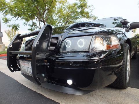 2003 Ford Crown Victoria - Ground-level view of Crown Victoria nose and wheel, push bar and halo projector lamp, white foglight lit.