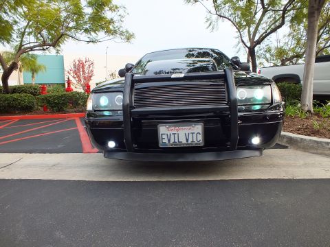 2003 Ford Crown Victoria - Symmetric front view of a low Crown Victoria, billet grille and grille guard, foglights illuminated.