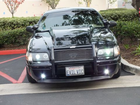 2003 Ford Crown Victoria - Front view of a Crown Victoria in a lot, grille guard and billet insert, halo headlights and foglights on.
