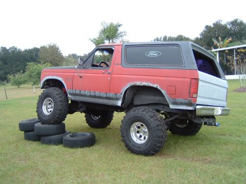 1983 Ford Bronco - This modified Ford Bronco is shown from a three-quarter front angle, lifted on large off-road tires.