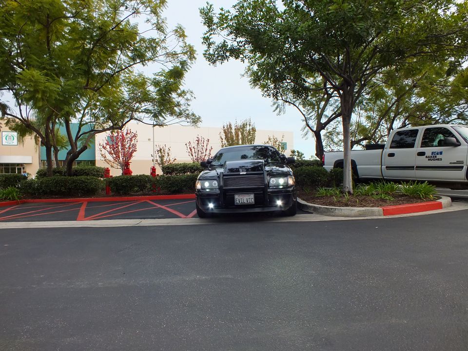 Lowered black Crown Victoria front view in parking lot with push bar and halo headlights
