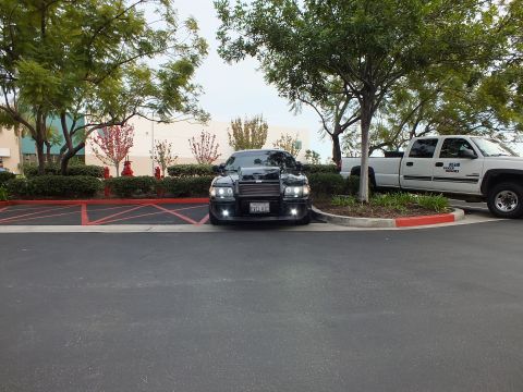 2003 Ford Crown Victoria - Wide shot of lowered black Crown Victoria with push bar parked against curb and shrubs.