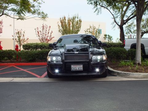 2003 Ford Crown Victoria - Lowered black sedan, billet grille and halo projectors lit, custom front guard, EVIL VIC plate.