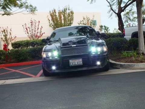 2003 Ford Crown Victoria - Lowered black Crown Victoria front view, halo headlights lit, custom grille guard, lot curb.