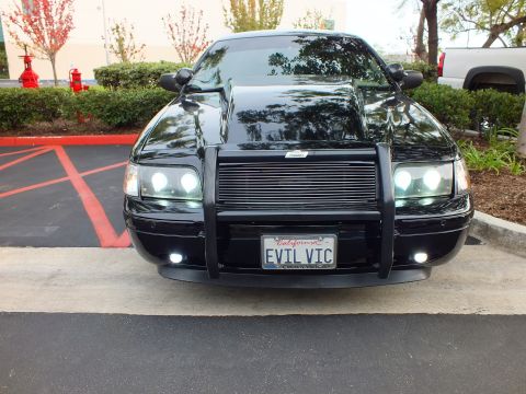 2003 Ford Crown Victoria - Front-on view of lowered black sedan, billet grille and halo projectors, custom grille guard.