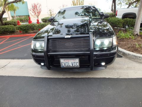 2003 Ford Crown Victoria - Lowered black Crown Victoria front-on, custom grille guard and billet grille, lot setting.
