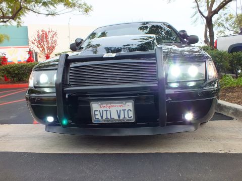 2003 Ford Crown Victoria - Lowered black sedan front view, halo projectors lit, plate frame reads Crown Victoria.