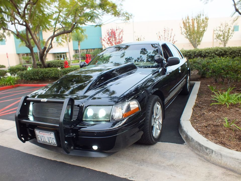 Black Crown Victoria front three-quarter in parking lot with grille guard and projector headlights